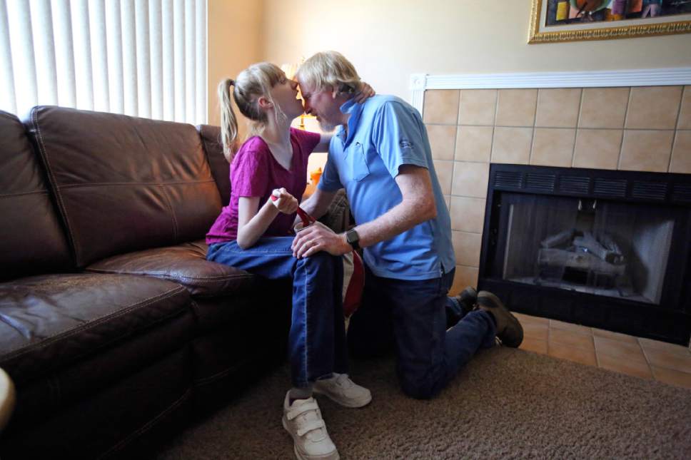 This June 6, 2017, photo, Utah resident Doug Rice, receives a hug from Ashley, his 24-year-old daughter at their home in West Jordan, Utah. Utah lawmakers balked again this year at joining more than half of all U.S. states and passing a broad medical marijuana law. Rice says Utah's approach means his daughter, who has a genetic condition, is missing out on the one drug that eliminates her frequent seizures. (AP Photo/Rick Bowmer)