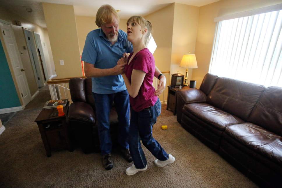 This June 6, 2017, photo, Utah resident Doug Rice, helps his daughter Ashley, 24, to walk at their home in West Jordan, Utah. Utah lawmakers balked again this year at joining more than half of all U.S. states and passing a broad medical marijuana law. Rice says Utah's approach means his daughter, who has a genetic condition, is missing out on the one drug that eliminates her frequent seizures. (AP Photo/Rick Bowmer)