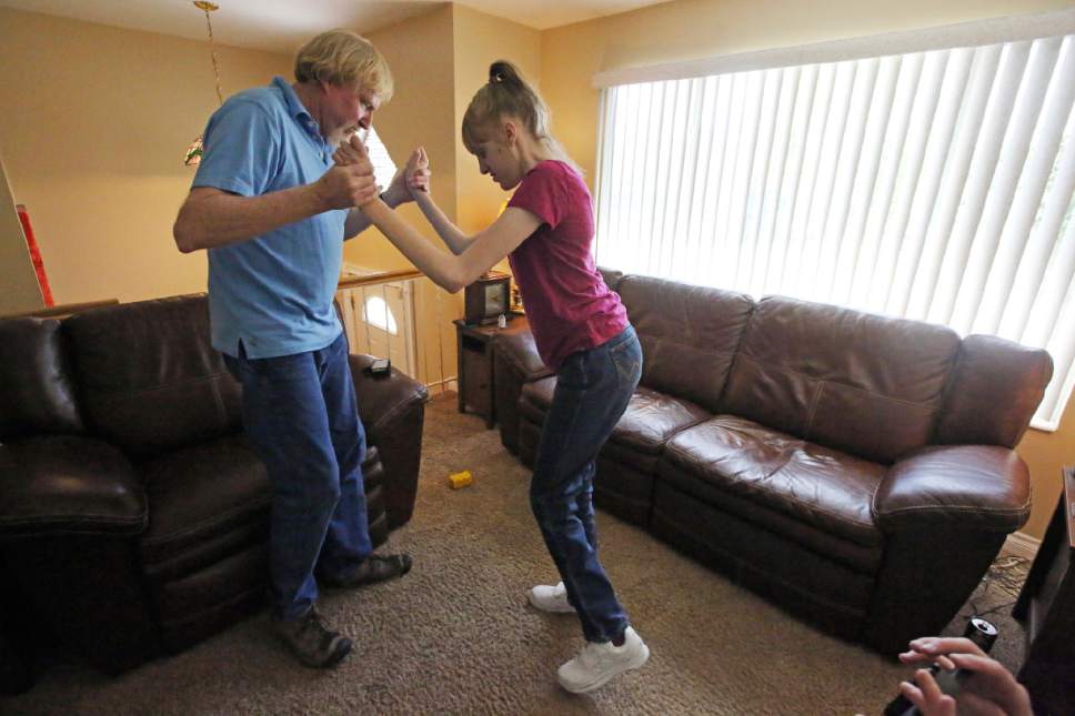 This June 6, 2017, photo, Utah resident Doug Rice, helps his daughter Ashley, 24, to walk at their home in West Jordan, Utah. Utah lawmakers balked again this year at joining more than half of all U.S. states and passing a broad medical marijuana law. Rice says Utah's approach means his daughter, who has a genetic condition, is missing out on the one drug that eliminates her frequent seizures. (AP Photo/Rick Bowmer)