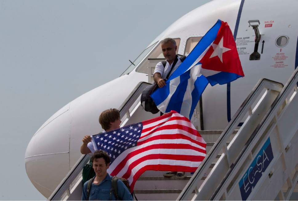 FILE- In this Aug. 31, 2016 file photo, two passengers deplane from JetBlue flight 387 waving a United States, and Cuban national flag, in Santa Clara. As President Donald Trump is expected to announce a reversal on the U.S. Cuba policy on Friday, June 16, 2017, Cubans are bracing for the worst. Across the island, people of all ages, professions and political beliefs expect rising tensions, fewer American visitors and a harder time seeing relatives in the U.S.(AP Photo/Ramon Espinosa, File)