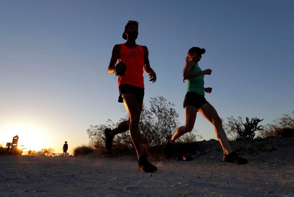 A couple runs through section of South Mountain Park at sunrise to avoid the excessive heat, Friday, June 16, 2017 in Phoenix. A record heat wave is rolling into Arizona, Nevada and California that threatens to bring 120-degree temperatures to Phoenix by early next week. (AP Photo/Matt York)