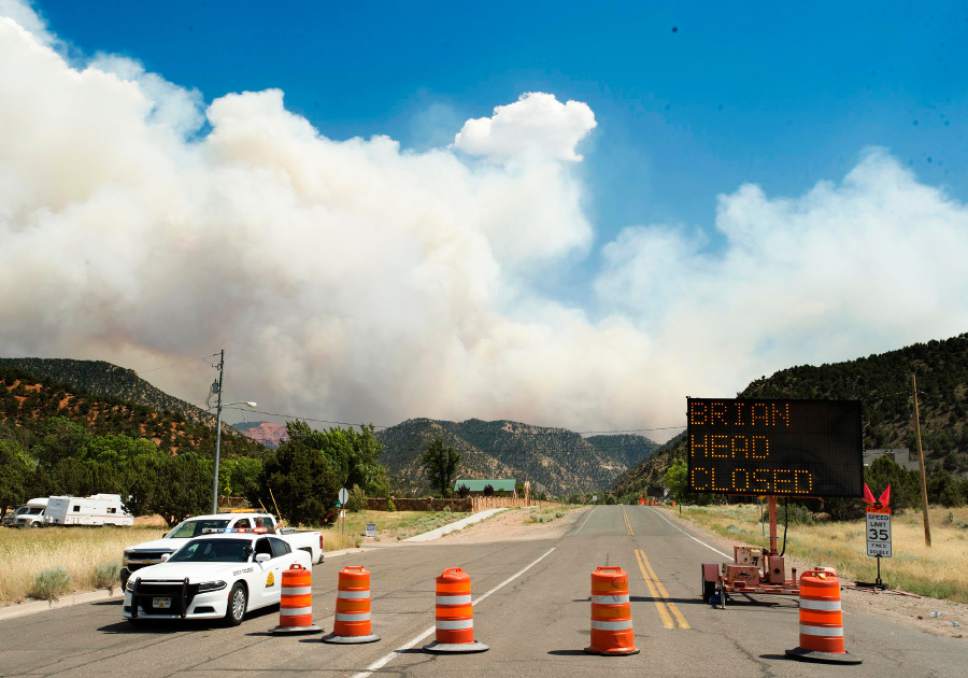 Rick Egan  |  The Salt Lake Tribune
Smoke billows in the afternoon winds behind the roadblock closing highway 143 to Brian Head, in Parowan on Wednesday.
