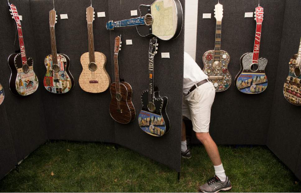 Leah Hogsten  |  The Salt Lake Tribune
Todd Perkins searches for business cards at his Utah Arts Festival booth, June 22, 2017.  Perkins creates unique guitar art from up-cycled materials to create one of a kind, themed custom art.   The Utah Arts Festival is the largest outdoor multi-disciplinary arts event in Utah, running through June 25, 2017 at the City and County Building grounds in downtown Salt Lake City.