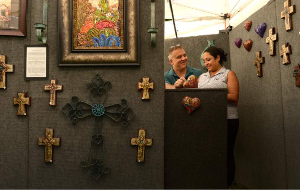 Leah Hogsten  |  The Salt Lake Tribune
Gabriel and Veronica Sandoval amid their unique artwork of intricate designs and landscapes drawn on aluminum and paint, using a technique called repousse. The Sandoval's share a laugh at their Arts Festival booth, June 22, 2017.  The Utah Arts Festival is the largest outdoor multi-disciplinary arts event in Utah, running through June 25, 2017 at the City and County Building grounds in downtown Salt Lake City.