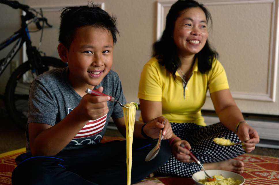 Scott Sommerdorf | The Salt Lake Tribune
Mu Say, a refugee from Burma, right, smiles as her nephew Teh, as he eats mohinga, a traditional noodle dish. Thursday, May 10, 2017.