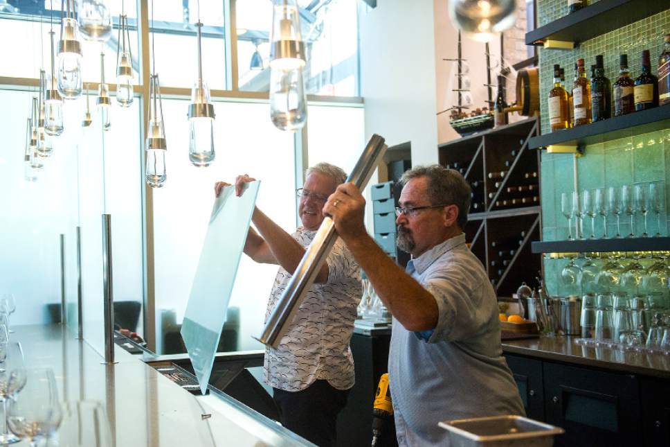 Chris Detrick  |  The Salt Lake Tribune
Owner Joel LaSalle, left, and Building Manager Mark Silvester tear down the Zion Curtain around the restaurant bar at Current Fish & Oyster in Salt Lake City on Saturday, July 1, 2017. A new law goes into effect on Saturday, allowing restaurants options other than the 7-foot opaque barrier intended to block children from seeing drinks being mixed. Restaurants can choose to keep the "Zion Curtain"; create a 10-foot buffer from the bar where minors are not allowed; or build a half-wall or railing, at least 42 inches high, that creates a delineation between the dining and liquor-dispensing areas.