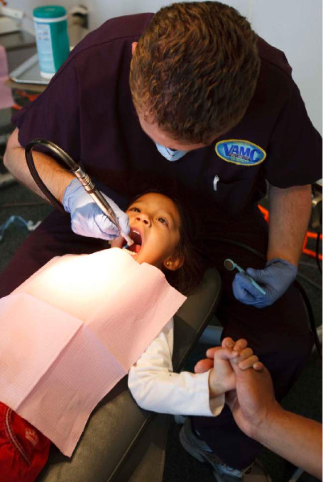 Trent Nelson  |  The Salt Lake Tribune

Amy Teresita Gomez holds her father's hand while Trevor Lindgren, a dentist volunteering his services, cleans her teeth Friday, July 31, 2009 during the Junior League CARE Fair at the Horizonte Instructional & Training Center.
