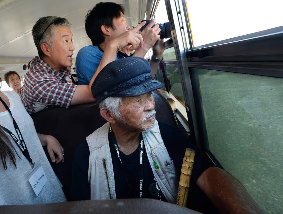 Scott Sommerdorf   |  The Salt Lake Tribune  
Chris Hirano, top, points out the Topaz Internment Camp as the bus taking them and others out to the actual site of the camp in Delta, Saturday, July 8, 2017. His father, 83 year-old Bobby Hirano who lived in the Topaz Internment Camp as a young boy, looks out the window of the bus at the place he lived during WWII. This was his first time back to Topaz since he left as a ten year old boy.