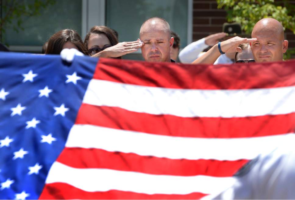 Scott Sommerdorf   |  The Salt Lake Tribune  
Sgt. Chad Reyes salutes as the flag draping his K-9 partner's casket is lifted to be folded at the memorial service for "Dingo," a Unified Police Department dog shot and killed in the line of duty July 6 while working with his K-9 handler Sgt. Chad Reyes, Saturday, July 15, 2017.