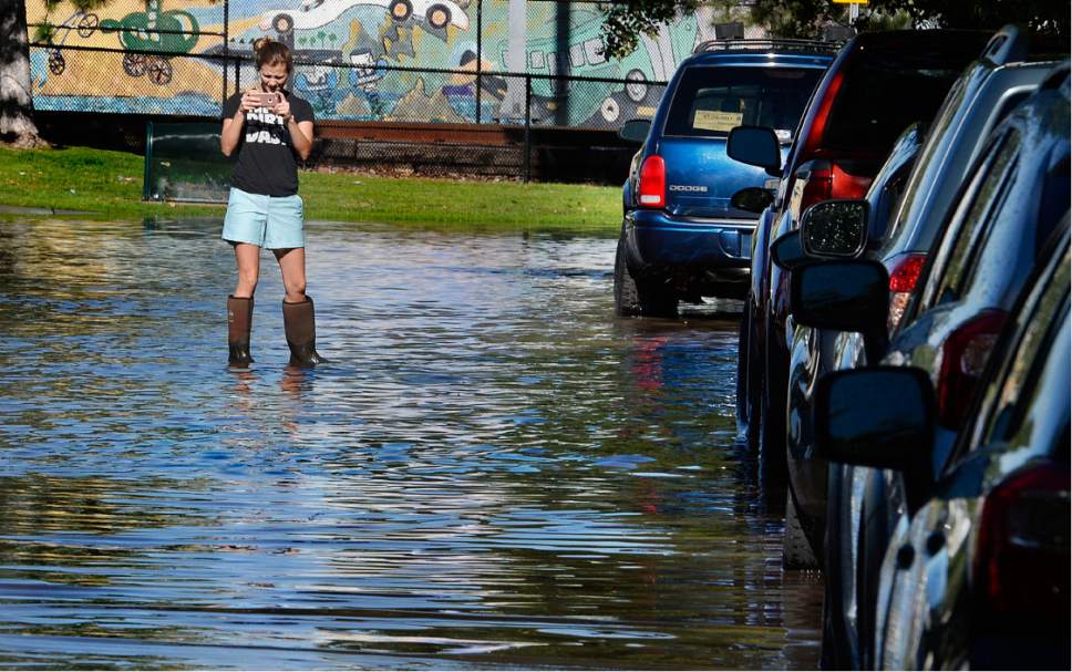 Scott Sommerdorf   |  The Salt Lake Tribune  
A Lucy Street resident got out into the flooded street in her boots to make a photo of the flooded street. Northbound Main Line TRAX trains were prevented from leaving the Ballpark TRAX station due to flooding, Wednesday, July 26, 2017.