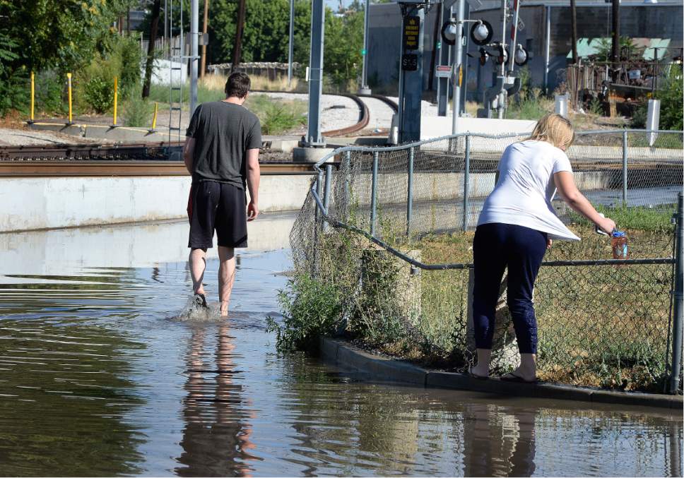 Scott Sommerdorf   |  The Salt Lake Tribune  
Lucy Street residents got out into the flooded street to try and walk around the corner to 200W. Northbound Main Line TRAX trains were prevented from leaving the Ballpark TRAX station due to flooding, Wednesday, July 26, 2017.