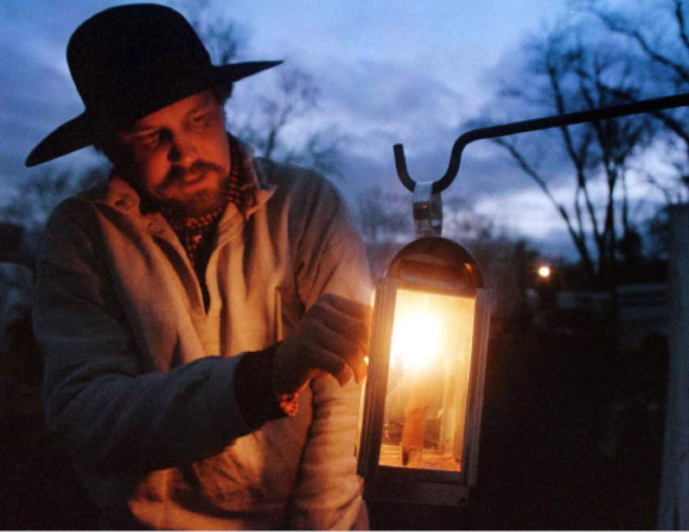 Rick Egan  | Tribune File Photo 

Steve Sorensen, Salt lake city, lights a lantern to give light to the cooks making scones for their Sunday night supper in Miller park.  Supper was finger food as all of the china and dinner ware was packed to hit the trail the next morning.