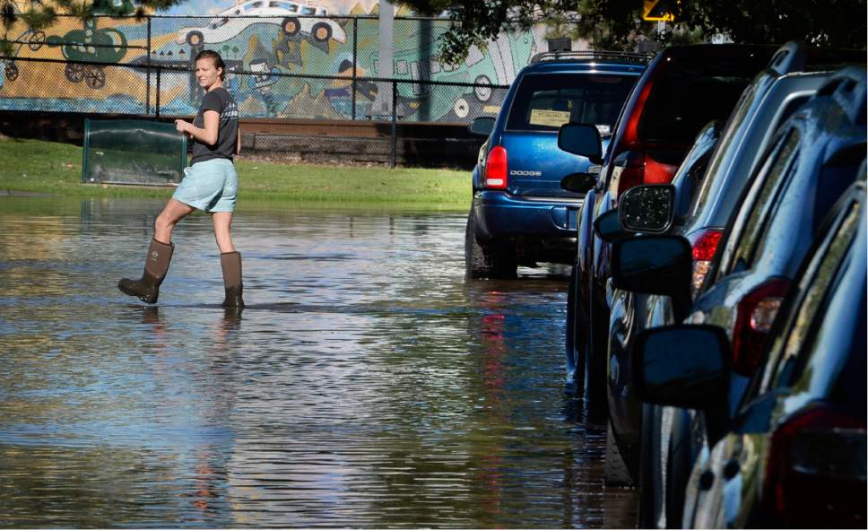 Scott Sommerdorf   |  The Salt Lake Tribune  
A Lucy Street resident got out into the flooded street in her boots to examine the flooded street. Northbound Main Line TRAX trains were prevented from leaving the Ballpark TRAX station due to flooding, Wednesday, July 26, 2017.