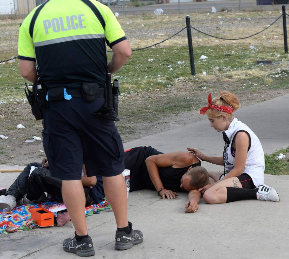 Al Hartmann  |  The Salt Lake Tribune
Salt Lake City police officer Sgt. Sam Wolf talks to people near their makeshift shelter and belongings along 300 S. and 500 W. Wednesday morning July 19.   He politely wakes up dozens of homeless camped on the sidewalks, telling them that they have to break down their camps and offers advice for help and rescources.   Camping on the street is a class B misdemeanor and can now be enforced.